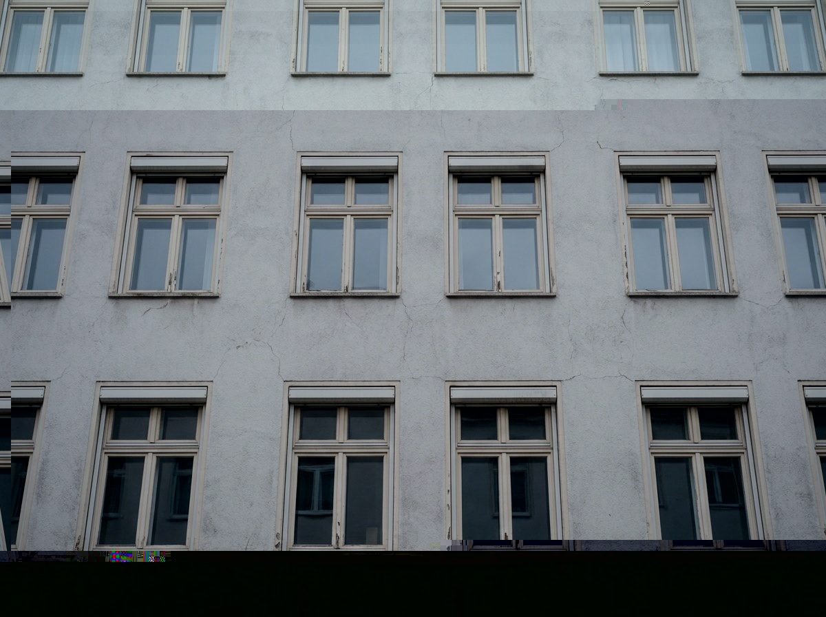 Regelmäßiges Fensterraster einer hellen Fassade in ruhigem Grau, Nahaufnahme ohne Beschriftung