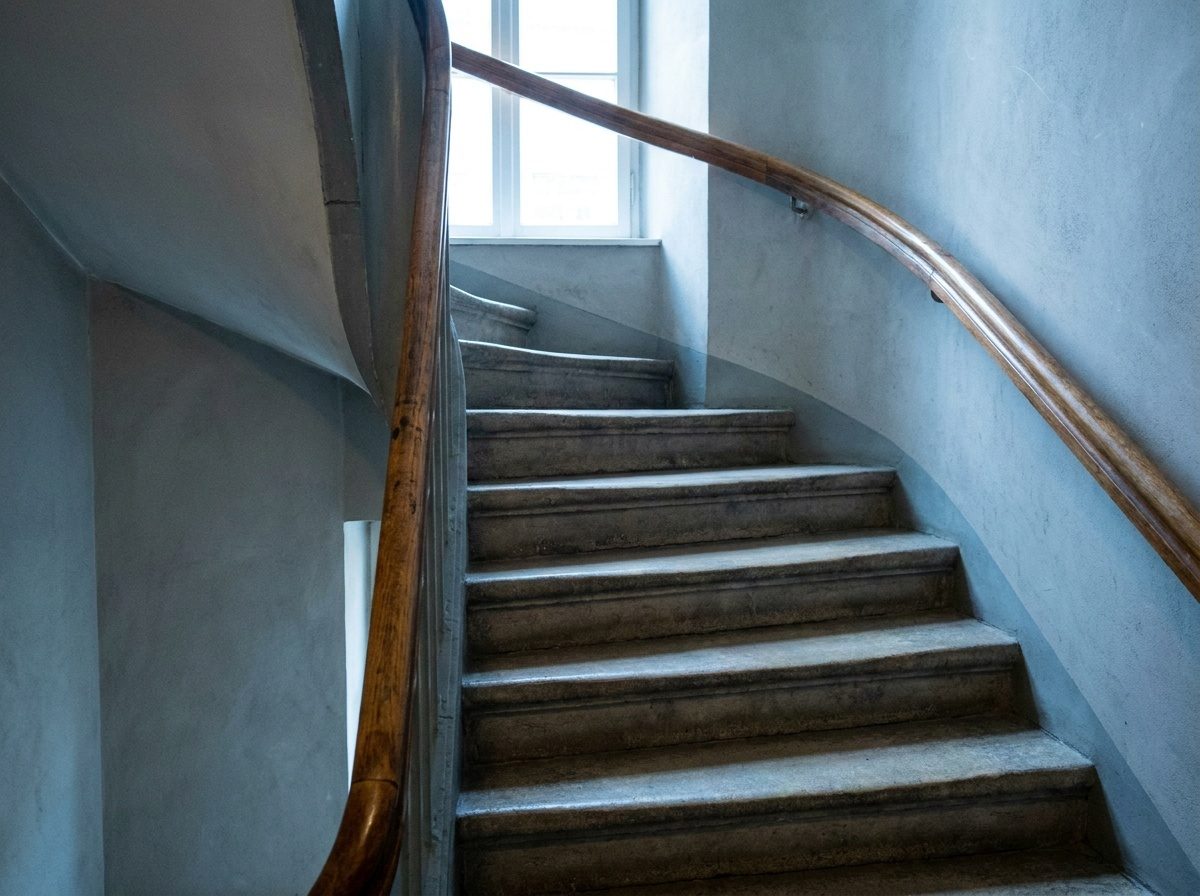 Gewendelte Treppe in hellem Stein mit gleichmäßigen Stufen, Detailaufnahme ohne Beschriftung
